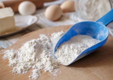 Ahşap tahta üzerinde mavi plastik kaşık buğday unu