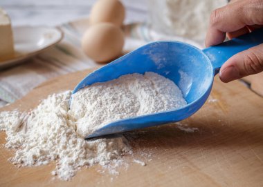 Ahşap tahta üzerinde mavi plastik kaşık buğday unu