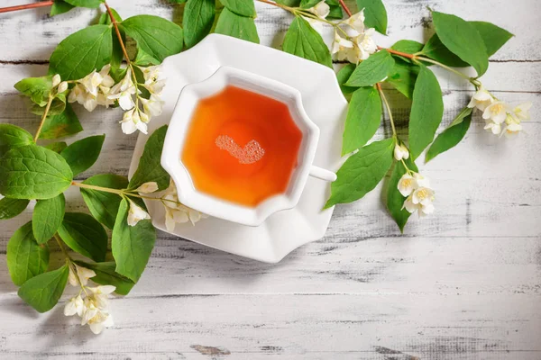 Чашка чая с жасминовыми цветами на белом столе — стоковое фото