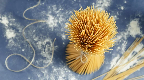 Pişmemiş makarna spagetti mor bir arka plan üzerinde — Stok fotoğraf