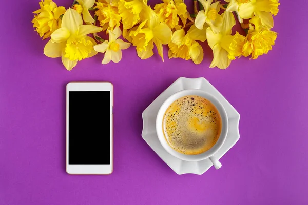 Koffiekopje Met Narcissus Bloemen Slimme Telefoon Kleurrijke Paarse Achtergrond Plat — Stockfoto