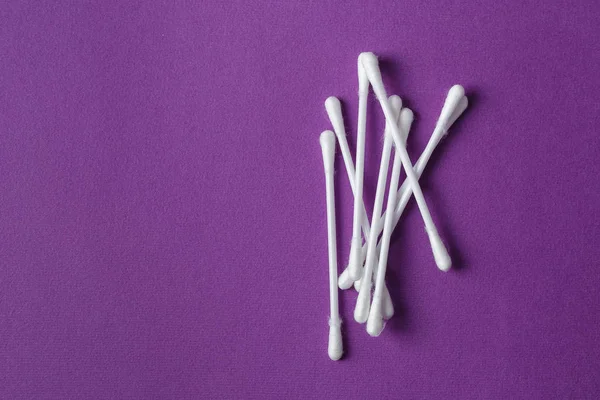 White plastic cotton swabs on purple background