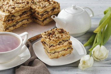 Fındıklı bir parça turta ve beyaz ahşap arka planda bir fincan çay.