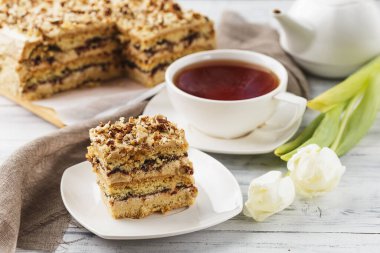 Fındıklı bir parça turta ve beyaz ahşap arka planda bir fincan çay.