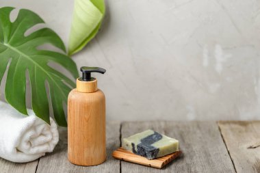 Etiketsiz ahşap pompa sabun şişesi ve iki parça kuru şampuan banyodaki ahşap masada fotokopi alanı olan sabun tabağı.