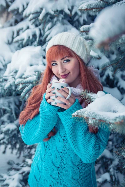 Donna tiene una tazza di caffè con marshmallow nella foresta invernale — Foto Stock