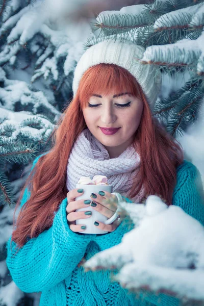 Donna tiene una tazza di caffè con marshmallow nella foresta invernale — Foto Stock