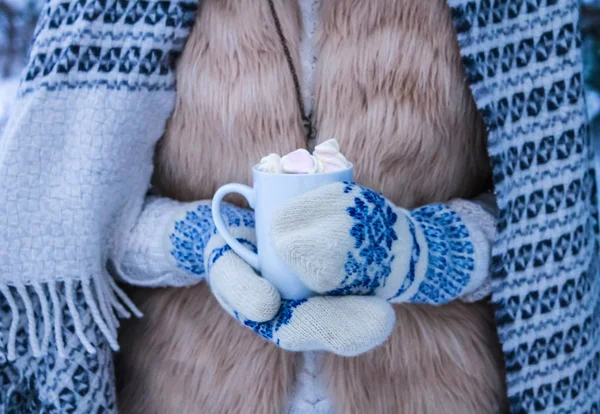 Женщина держит чашку кофе с зефиром в зимнем лесу — стоковое фото