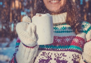 Kadın kahve hatmi ile kış orman içinde tutar.