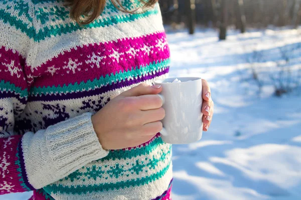 Женщина держит чашку кофе с зефиром в зимнем лесу — стоковое фото