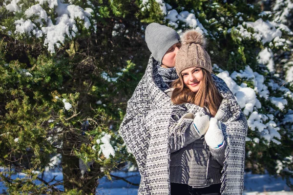 Verliefde paar bedekt met deken knuffels in winter forest — Stockfoto