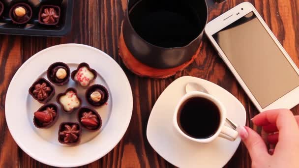 Drinking coffee with chocolate candies — Stock Video