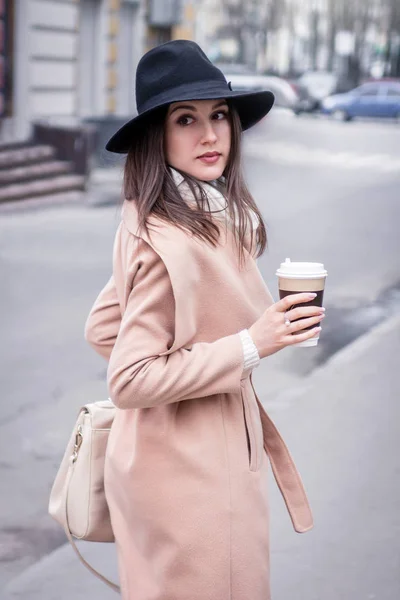 Mujer joven camina por la ciudad con una taza de café — Foto de Stock