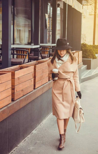 Mujer joven camina por la ciudad con una taza de café — Foto de Stock