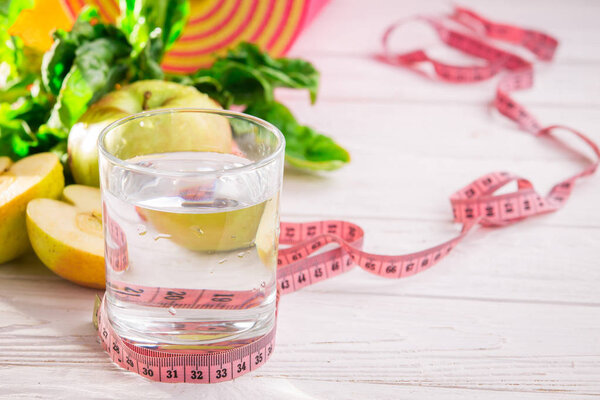 Yoga mat, water fruits and vegetables on a wooden background.