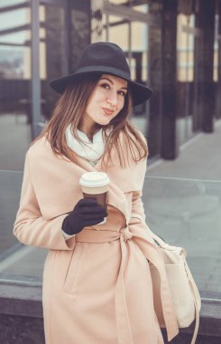 Kadın bir fincan kahve tutuyor.