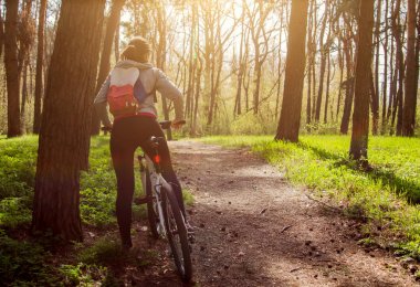 Ormanda bisiklet süren genç bir kadın.