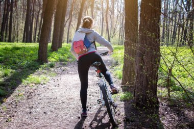 Ormanda bisiklet süren genç bir kadın.