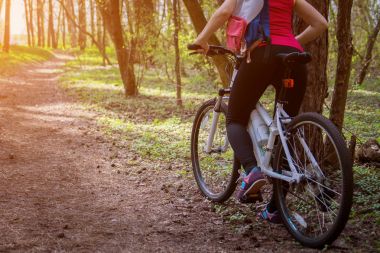 Ormanda bisiklet süren genç bir kadın.