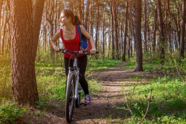 Ormanda bisiklet süren genç bir kadın.