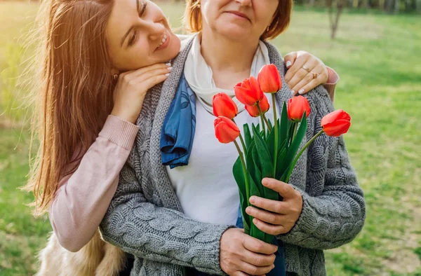 Tochter schenkt ihrer Mutter Tulpen. Muttertagsgeschenk — Stockfoto