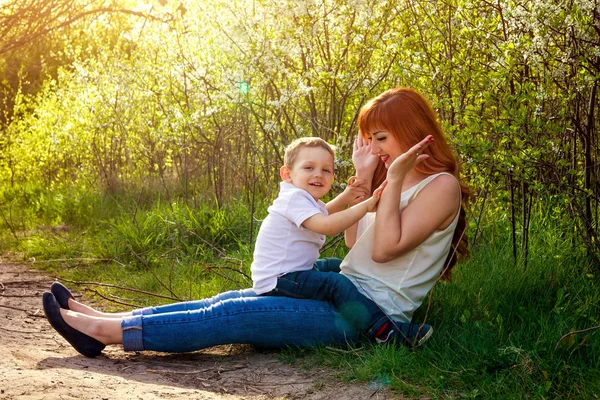 Młoda matka bawi się jej synka w ogrodzie. Koncepcja dzień matki — Zdjęcie stockowe
