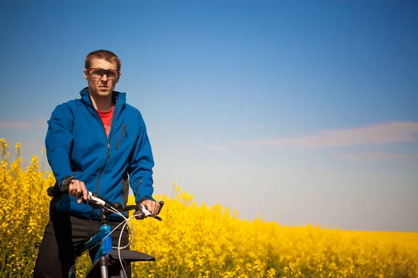 Jovens passeios de bicicleta no campo de colza — Fotografia de Stock