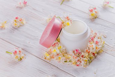 Çiçeklerle çevrili krem kavanoz