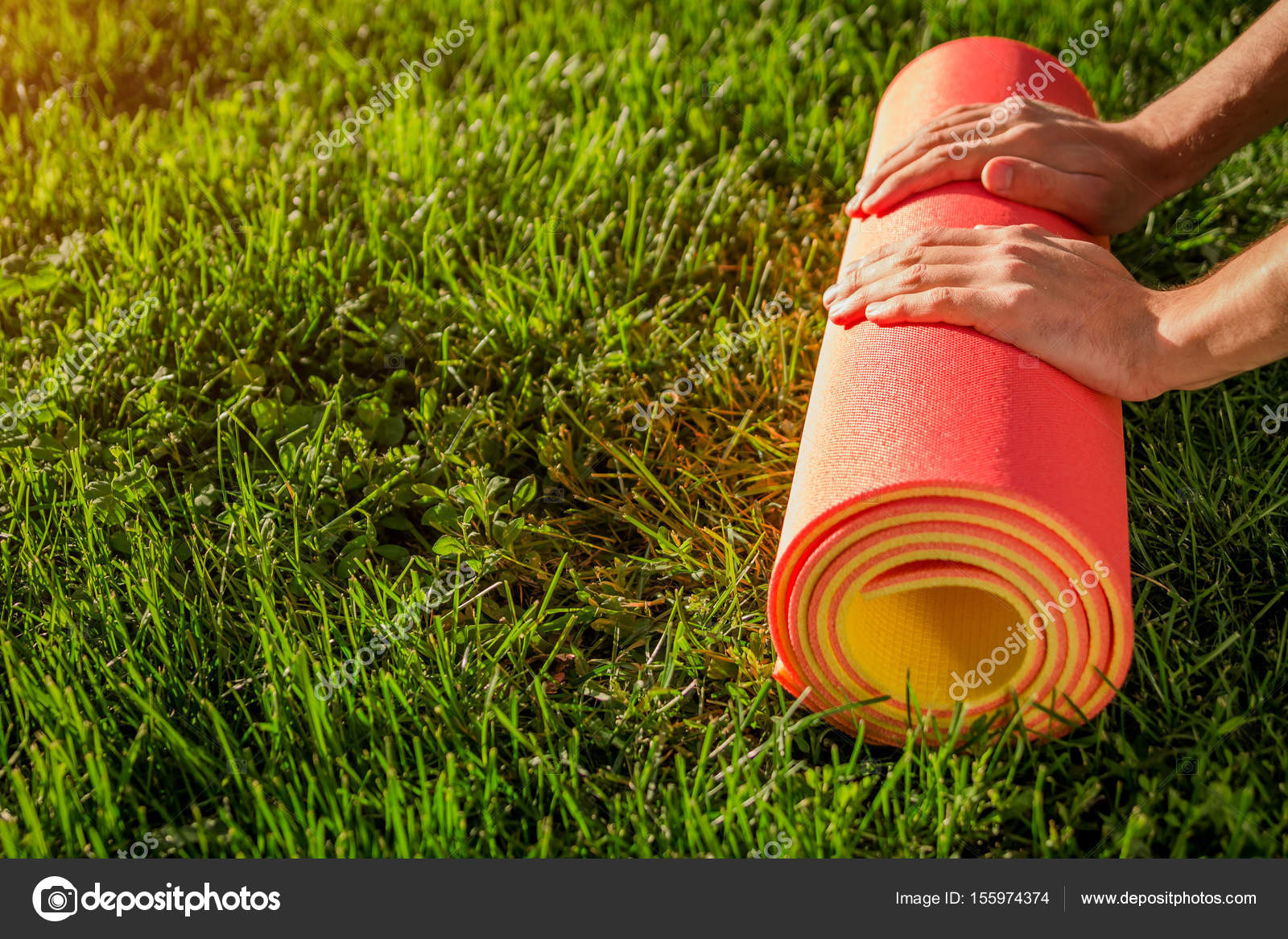 plakband Omgeving Melodramatisch Man rolls yoga mat on the grass Stock Photo by ©maryviolet 155974374