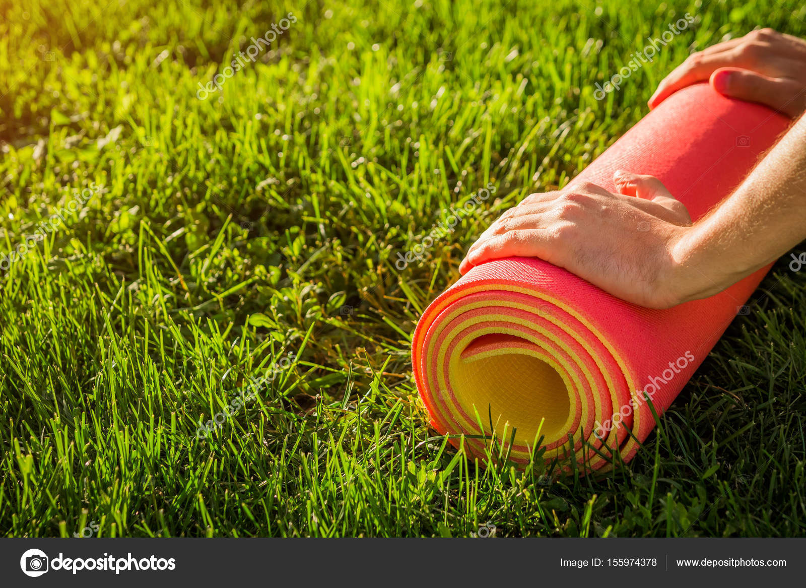 Man Rolls Yoga Mat On The Grass Stock Photo C Maryviolet 155974378