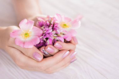 Kadın pembe manikür ile çiçek tutan