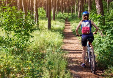 Ormanda bisiklet süren genç bir kadın.