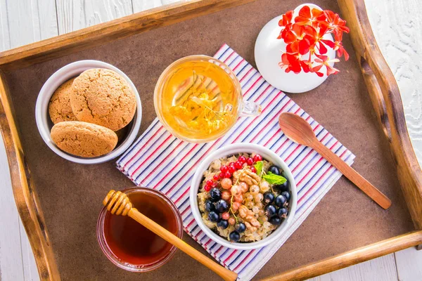 Haferbrei mit Beeren, Tee und Keksen zum Frühstück — Stockfoto