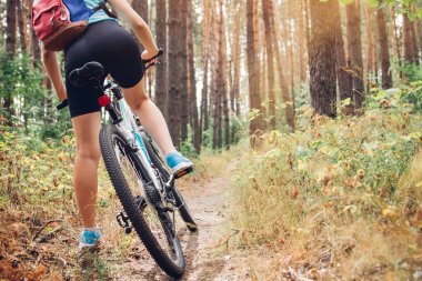 Ormanda bisiklet süren genç bir kadın.