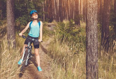 Ormanda bisiklet süren genç bir kadın.