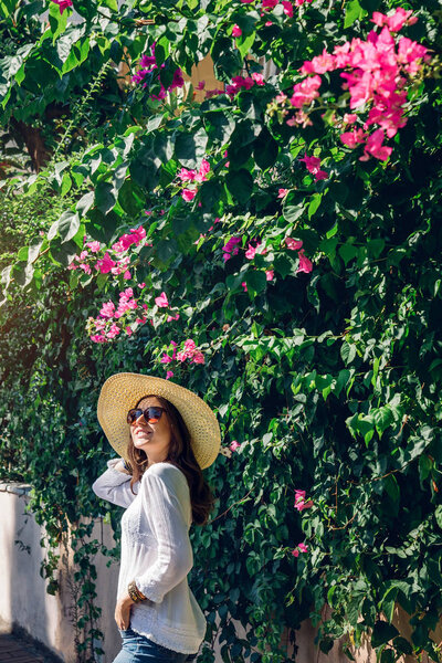 Young woman walking under bougainvillea flowers