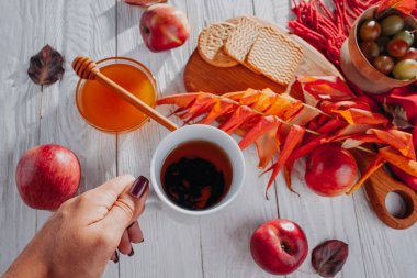 Kadın bisküvi ve bal ile sıcak çay içer. Sonbaharda hasat