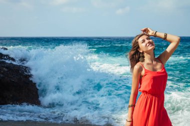 Güzel kadın uzak dalgalar kumsalda çalışır.