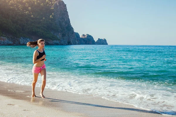 Genç bir kadın sahilde koşuyor.