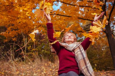 Orta yaşlı kadın ormanda yaprakları atma