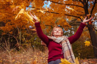 Orta yaşlı kadın ormanda yaprakları atma