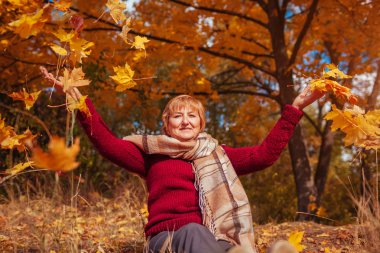 Orta yaşlı kadın ormanda yaprakları atma