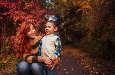 Mutlu anne ve yürüyüş ve having fun sonbahar ormanda küçük oğlu.