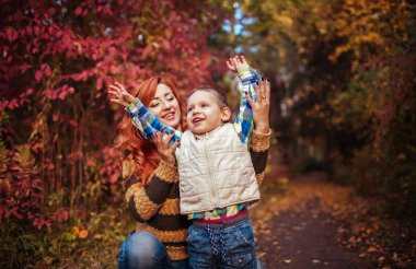 Mutlu anne ve yürüyüş ve having fun sonbahar ormanda küçük oğlu.