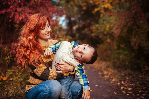 Mutlu anne ve yürüyüş ve having fun sonbahar ormanda küçük oğlu. — Stok fotoğraf