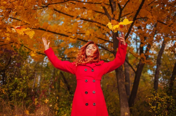 Молодая женщина бросает листья в лесу — стоковое фото