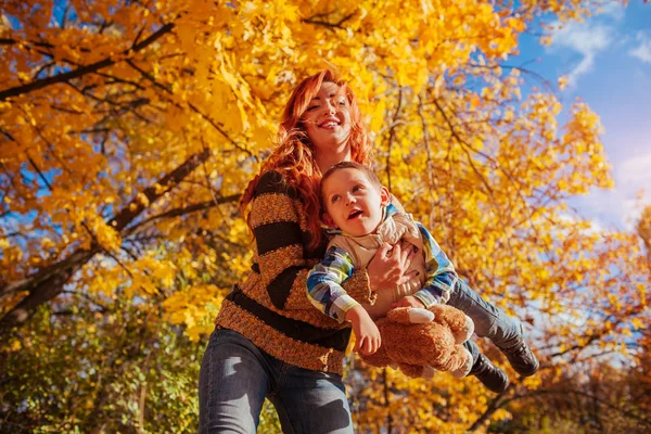 Mutlu anne ve yürüyüş ve having fun sonbahar ormanda küçük oğlu.
