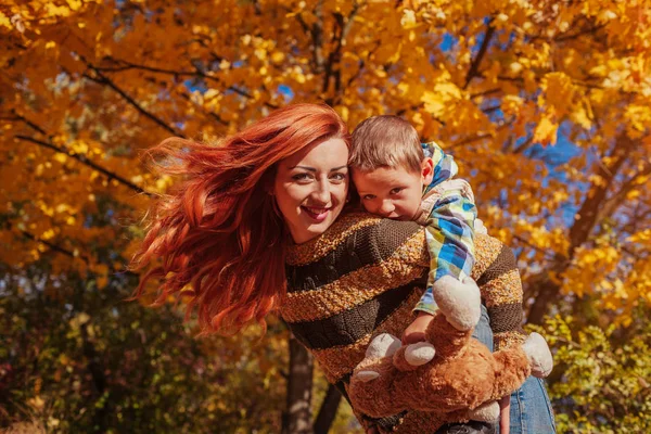 Mutlu anne ve yürüyüş ve having fun sonbahar ormanda küçük oğlu.