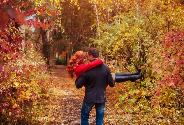 Genç çift sonbahar ormanda eğleniyor. Adam kadını kollarına tutar. — Stok fotoğraf