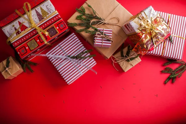 Caixas de presente decoradas com ramos de abeto no fundo vermelho . — Fotografia de Stock